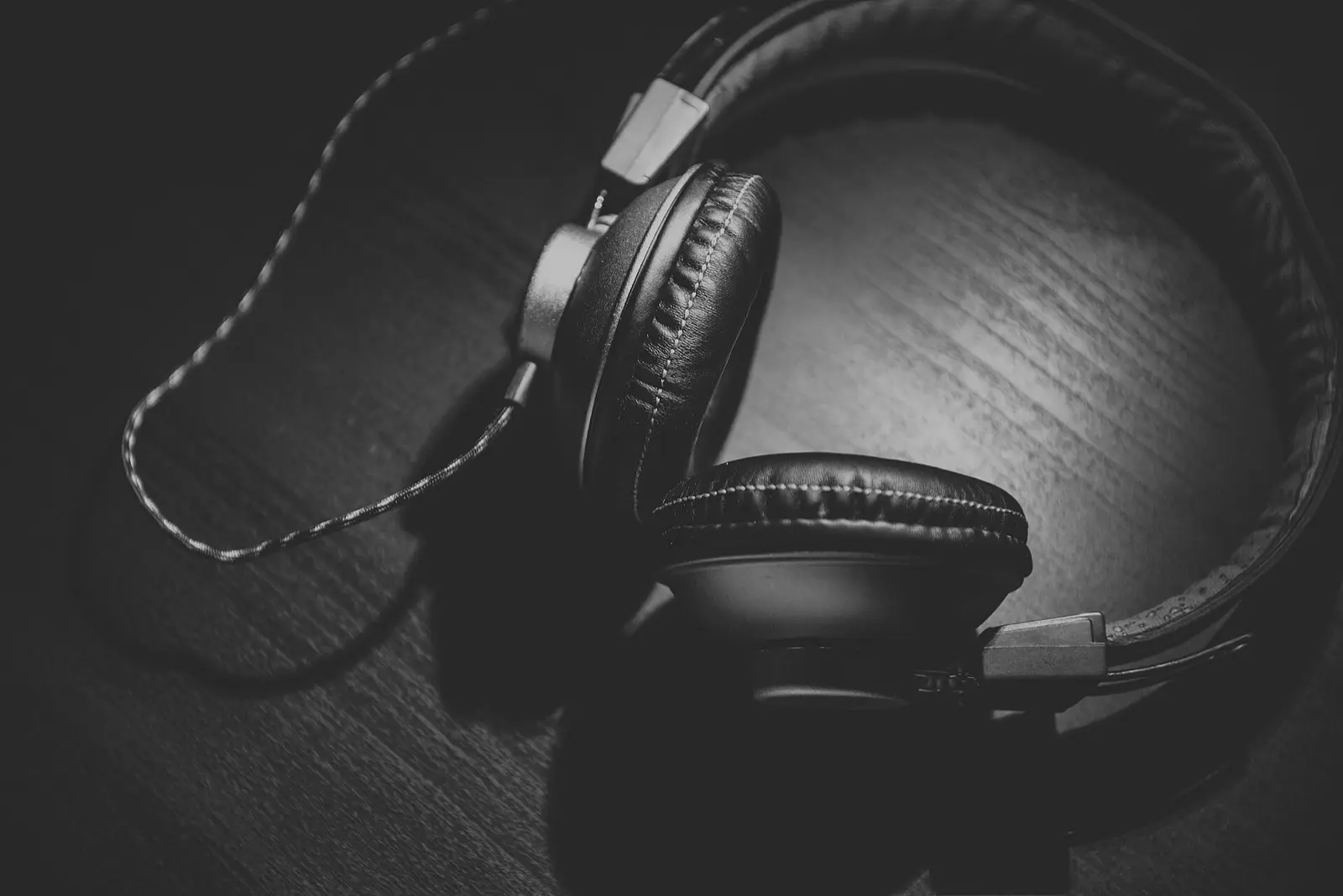 Headphones resting on a wooden table, in black and white
